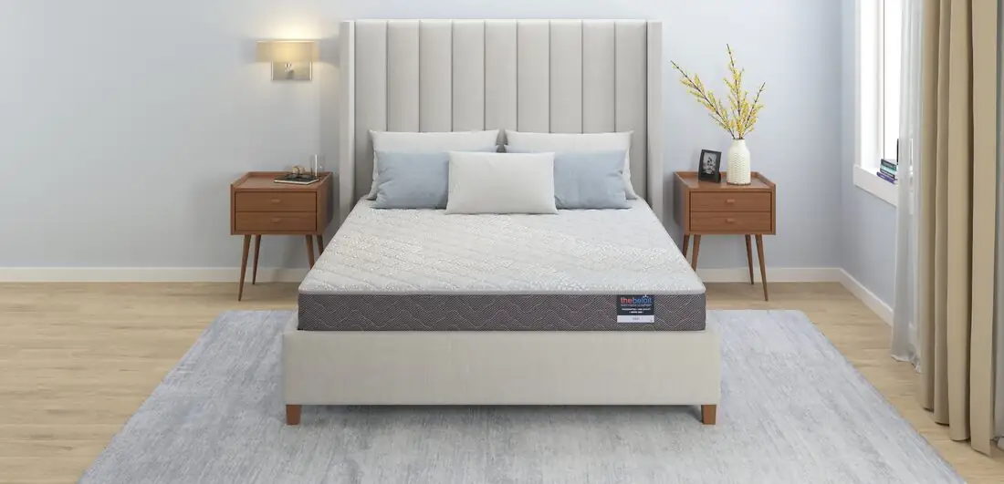 A finished Beloit custom mattress made up on a bed in a calm, sunlit bedroom