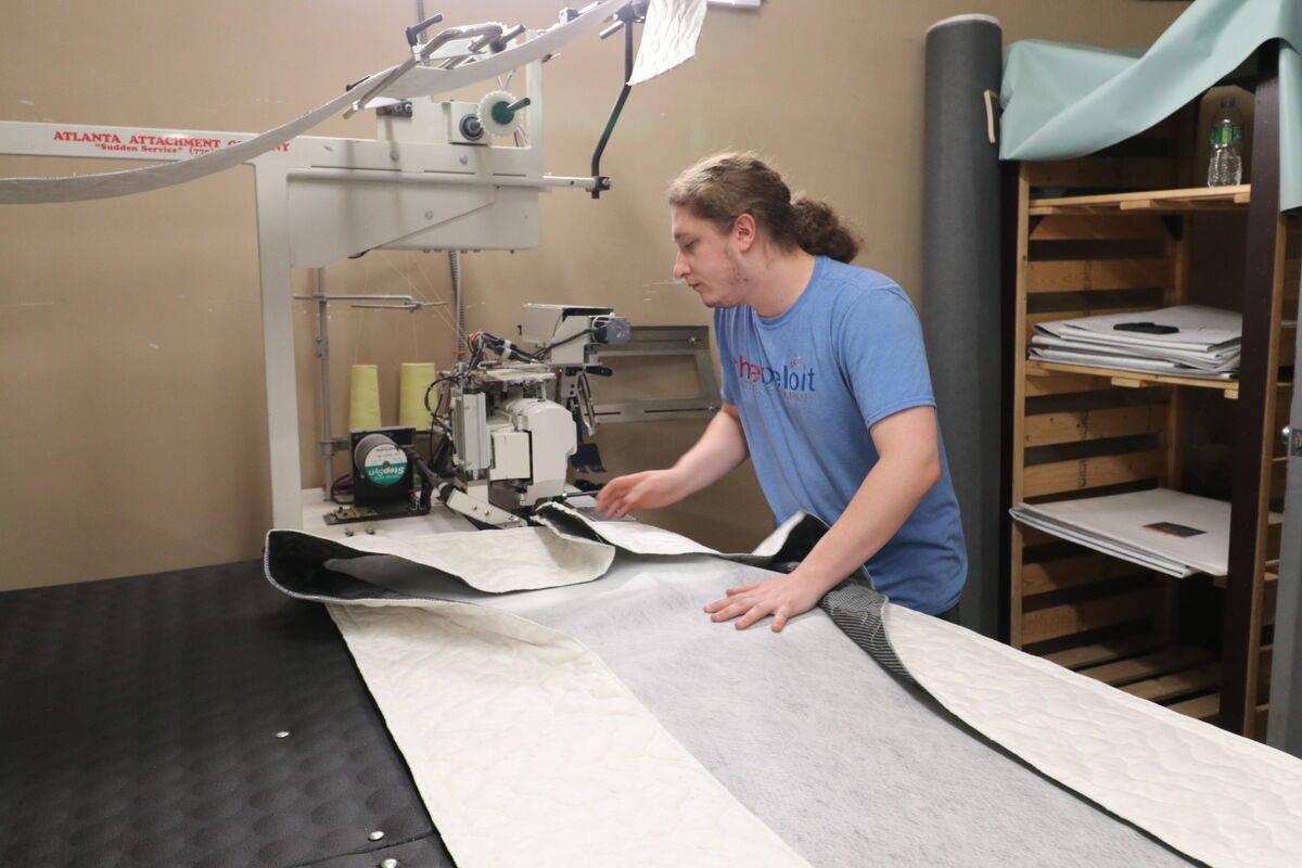 A Beloit bedmaker feeding fabric through the long-arm machine at the cutting table