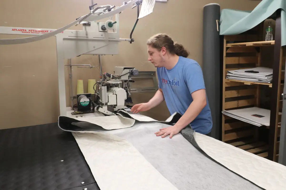 A Beloit bedmaker feeding fabric through the long-arm machine at the cutting table