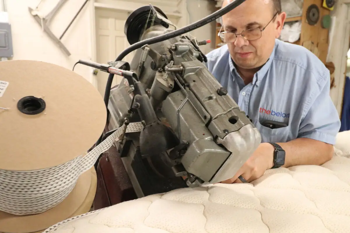 A bedmaker tufting a mattress