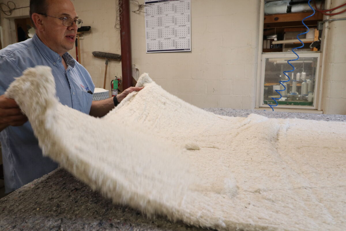 A bedmaker layering natural wool batting into a mattress